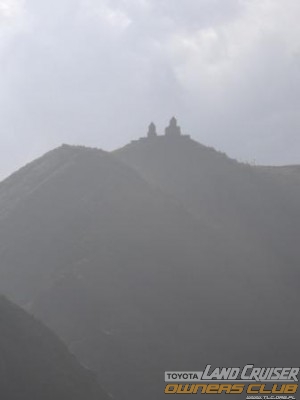 Kazbegi widok na klasztor za nim w chmurach Kazbek 5047 m n.p.m.